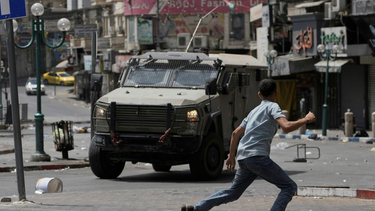 Un palestino huye ante la llegada de un blindado de Israel en Nablus.