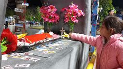 Una pequeña deposita una flor junto a la imagen de la Difunta Correa que fue ubicada en la plaza de Caucete durante la reciente Cabalgata de la Fe.