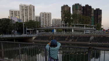 Una mujer toma una foto al complejo incendiado en Hong Kong-