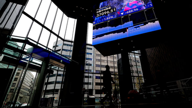 La silueta de un hombre bajo una pantalla que muestra la media bursátil japonesa Nikkei en Tokio.