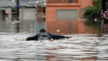 Un hombre se desplaza sobre una tabla en el agua en medio de las inundaciones que azotan Brasil.